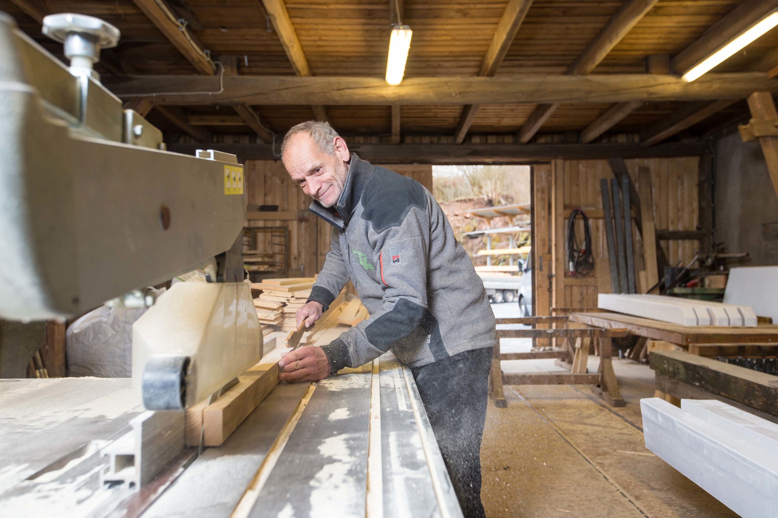 Der Zimmermeister Andreas Donner schneidet einen Holzbalken auf Maß.