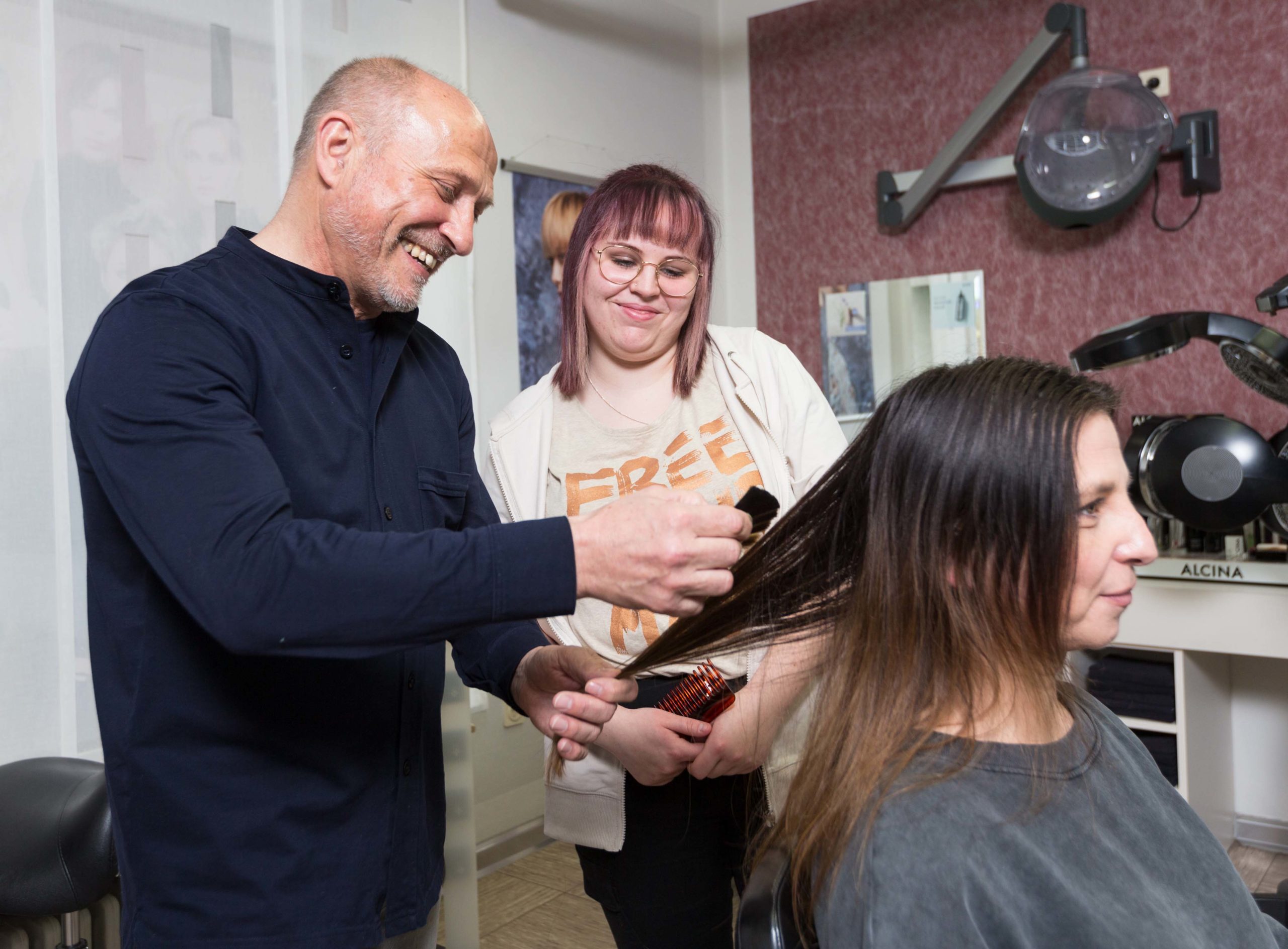 Salon-Inhaber Matthias Hoffmann gibt der Auszubildenden Lara Seifert Tipps, was es bei der Haarstruktur der Kundin zu beachten gibt